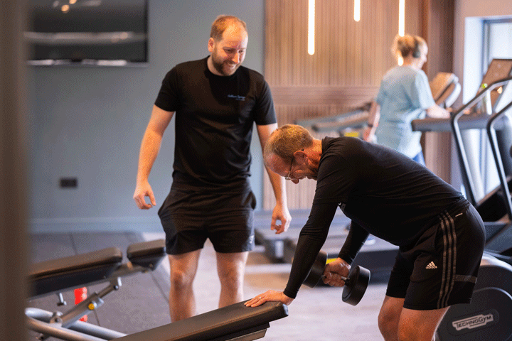 A man lifting weight sin gym with a personal trainer
