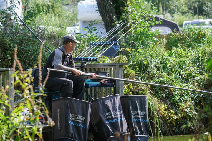 Man Sat Down Fishing By A Pond Beside Foliage