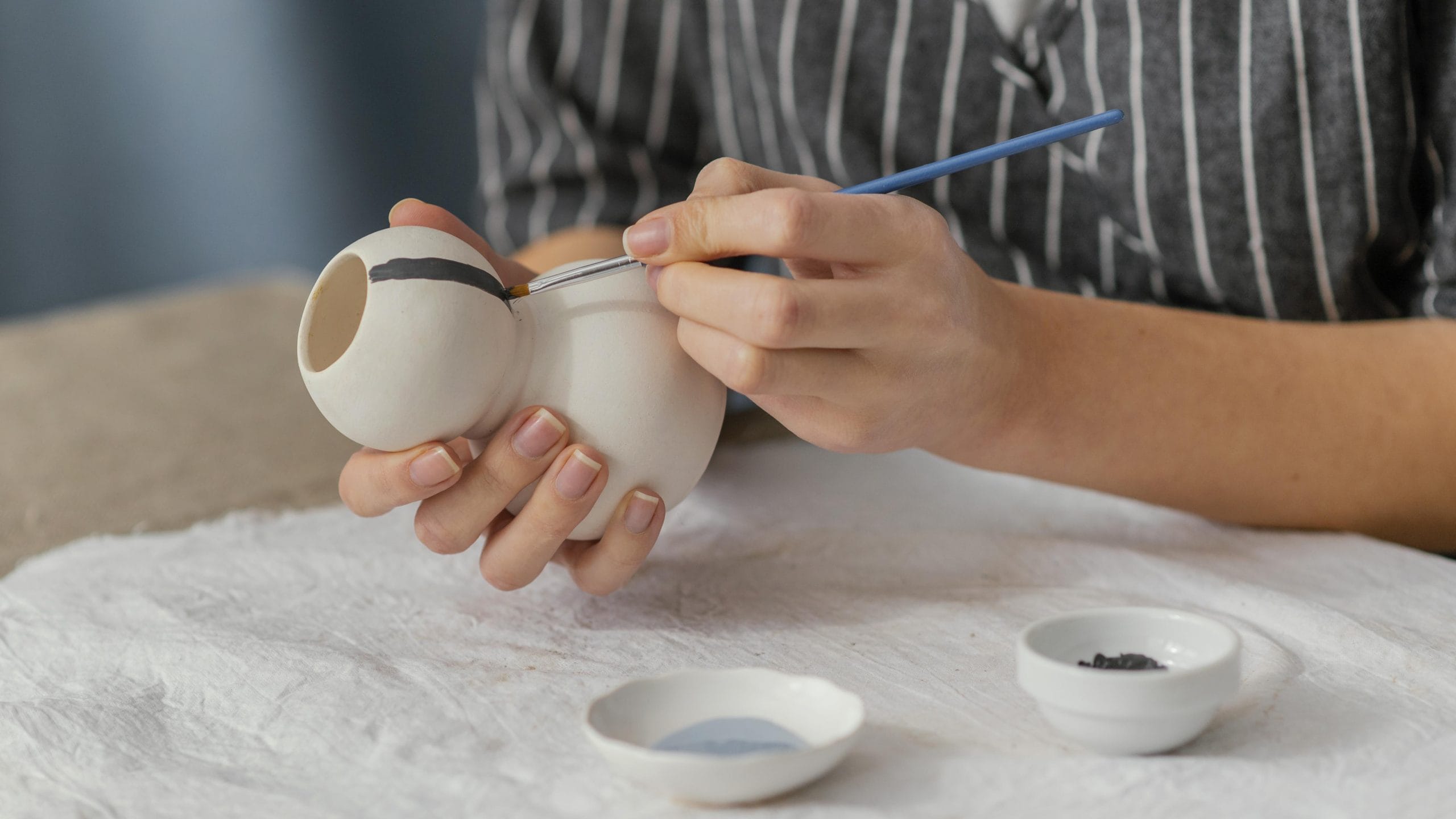 close up hands painting a pottery item